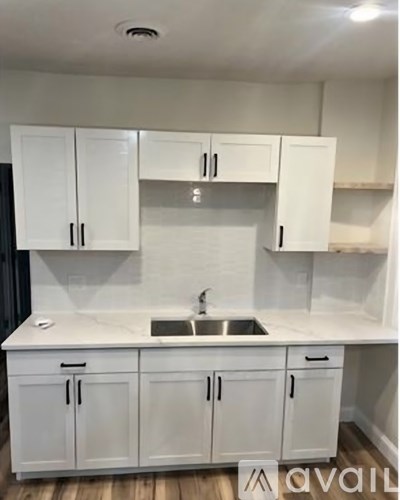 A kitchen with white cabinets and a marble countertop.
