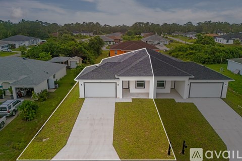 A house with a brown roof and a white garage door is surrounded by greenery.