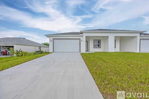 A modern house with a large driveway in front.
