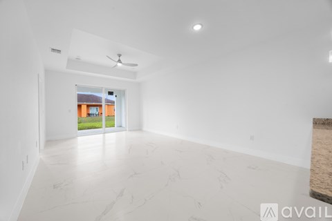 A spacious room with a ceiling fan and a view of a house through a window.