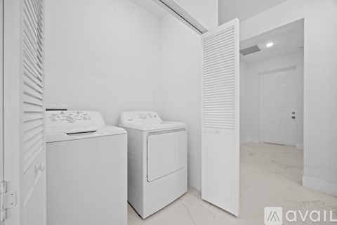 Two white front load washing machines in a laundry room.