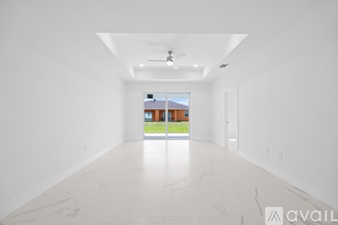 A spacious room with white walls and a marble floor leading to a balcony.