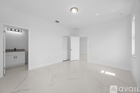 A spacious empty room with a marble floor and white walls.