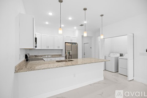A modern kitchen with granite countertops and white cabinets.