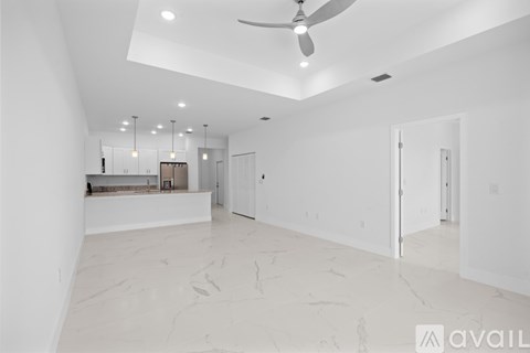 A spacious, empty room with a marble floor and a ceiling fan.