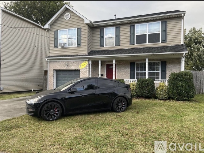 A black car is parked in front of a two-story house.