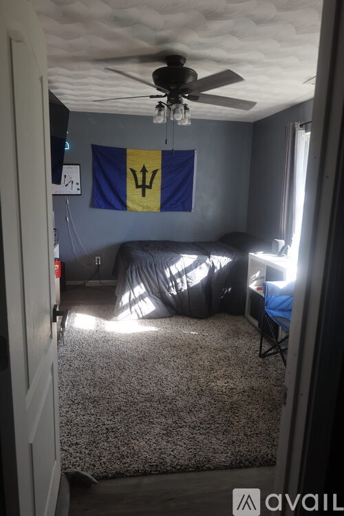 A room with a ceiling fan and a flag hanging from the ceiling.