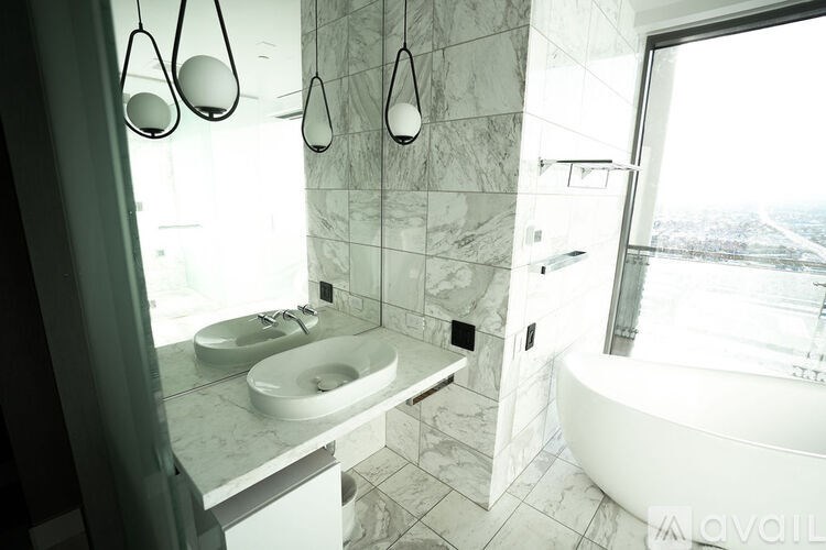 A bathroom with a tub, sink, and a window overlooking a cityscape.