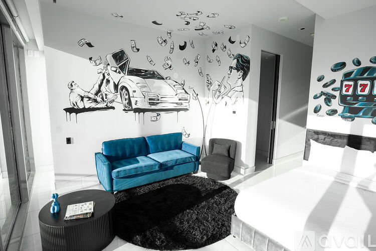 A living room with a blue couch and a painting of a man with a car and money.