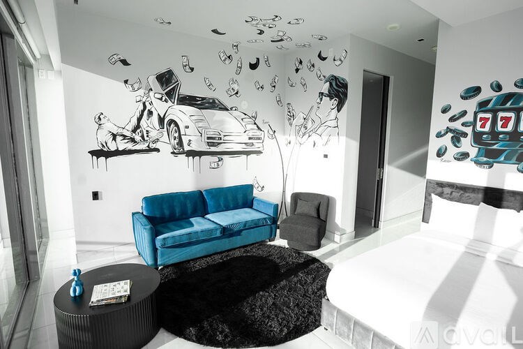 A living room with a blue couch and a painting of a man with a car and money.