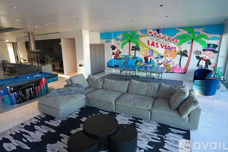 A living room with a pool table and a mural of a Las Vegas sign.