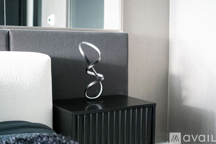 A modern silver ring sits on a black box.