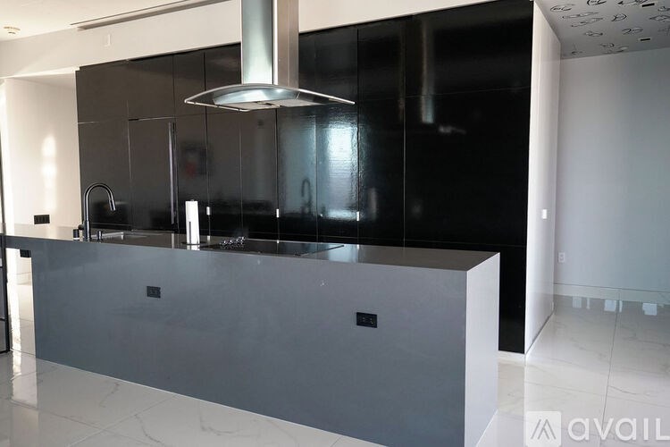 A modern kitchen with a dark countertop and a stainless steel range hood.
