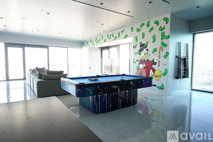 A room with a pool table and a wall with cartoon characters on it.