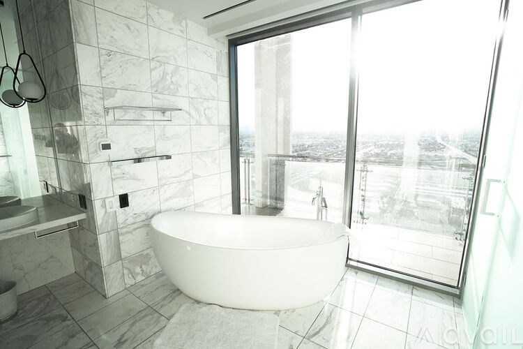 A white bathroom with a tub and a window overlooking a city.