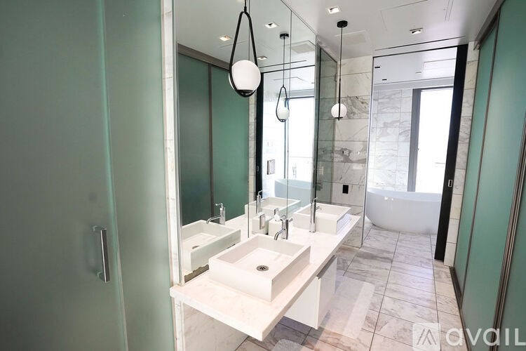 A modern bathroom with a white sink and a glass shower area.