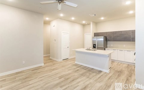 A spacious kitchen and living room with a television and wooden flooring.
