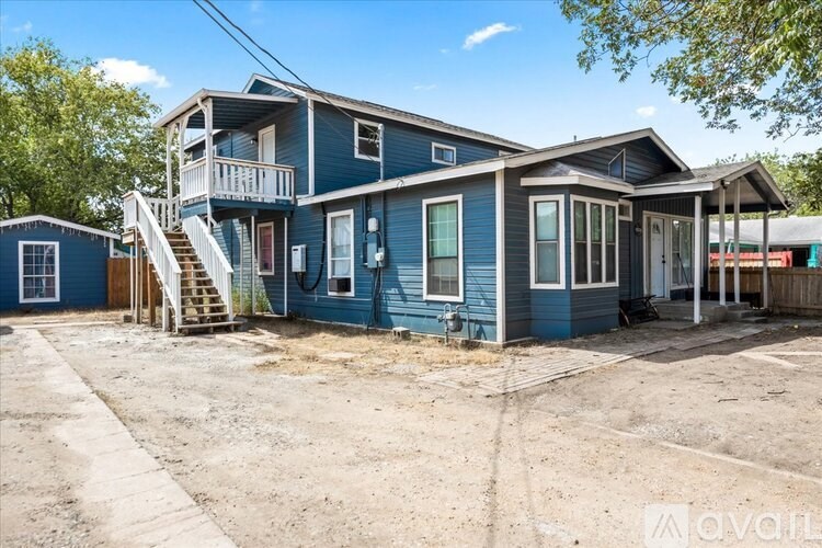 A blue house with a porch and a small shed.
