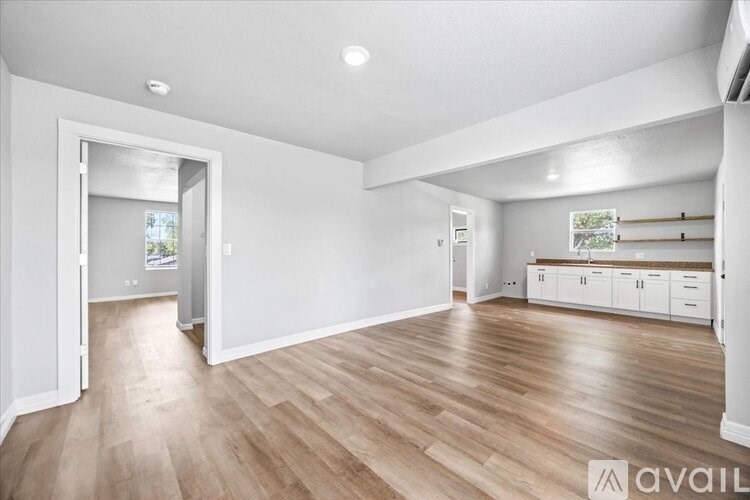 A spacious room with wooden flooring and white walls.