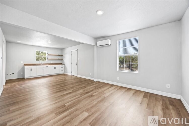 A spacious room with wooden flooring and white walls.