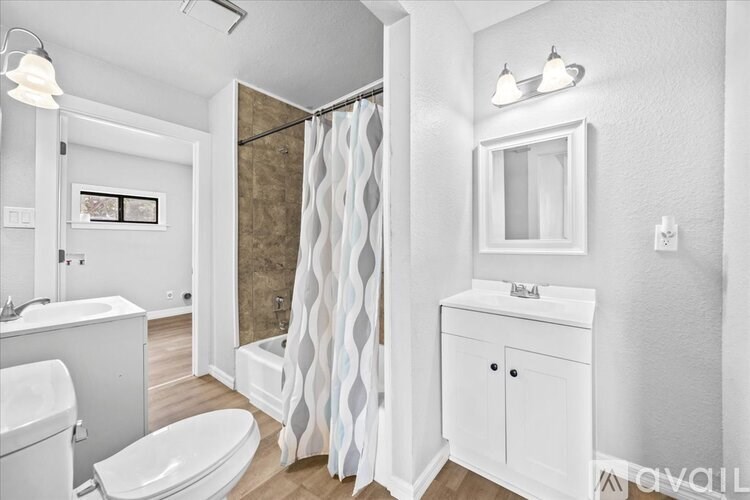 A white bathroom with a toilet, sink, and shower.