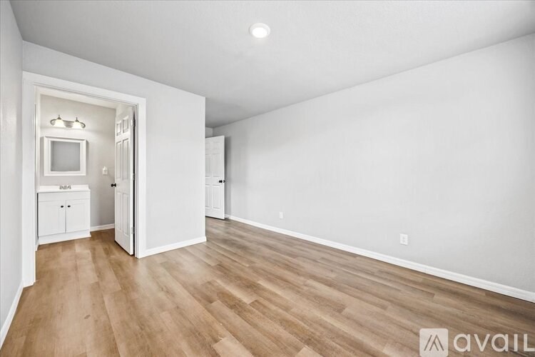 A spacious room with wooden flooring and white walls.