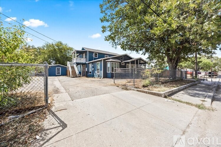 A blue house with a fence and a tree in front of it.