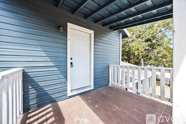 A white door is on the porch of a house with blue siding.