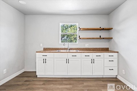 A kitchen with white cabinets and a window.