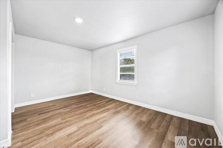 A room with wooden flooring and a picture frame on the wall.