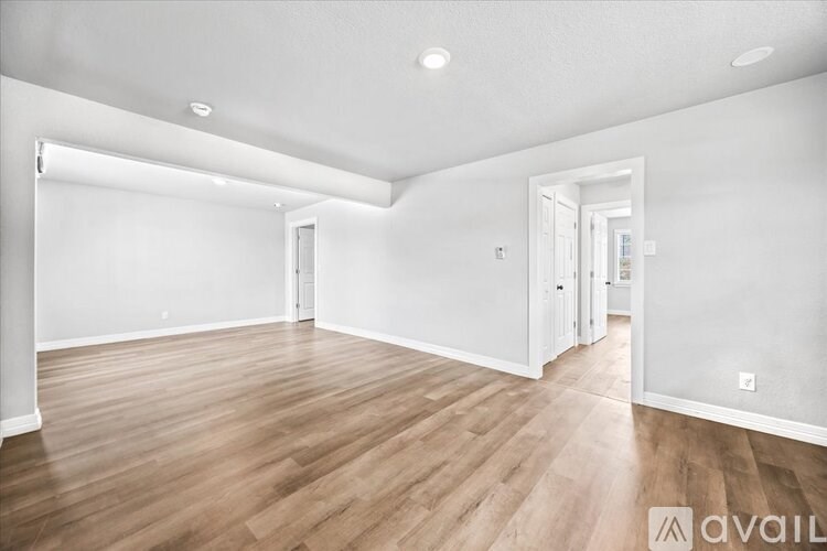 A spacious room with wooden flooring and white walls.