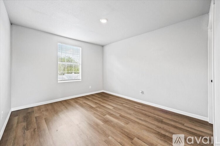 A room with wooden flooring and a window with blinds.
