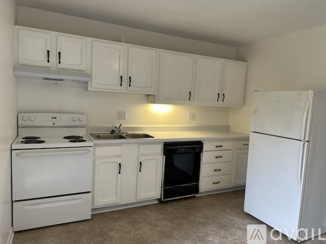 A white kitchen with a stove, sink, and refrigerator.