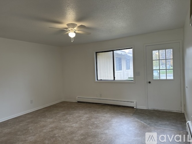 A room with a ceiling fan and a window with blinds.