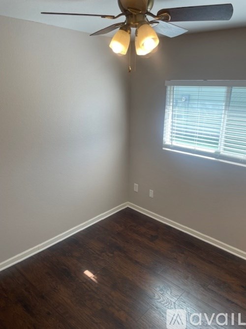 A room with a ceiling fan and a window with blinds.