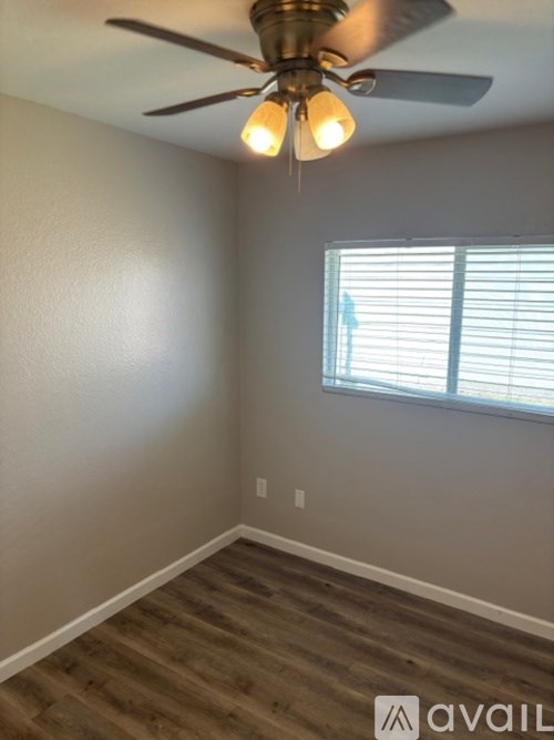 A room with a ceiling fan and a window with blinds.