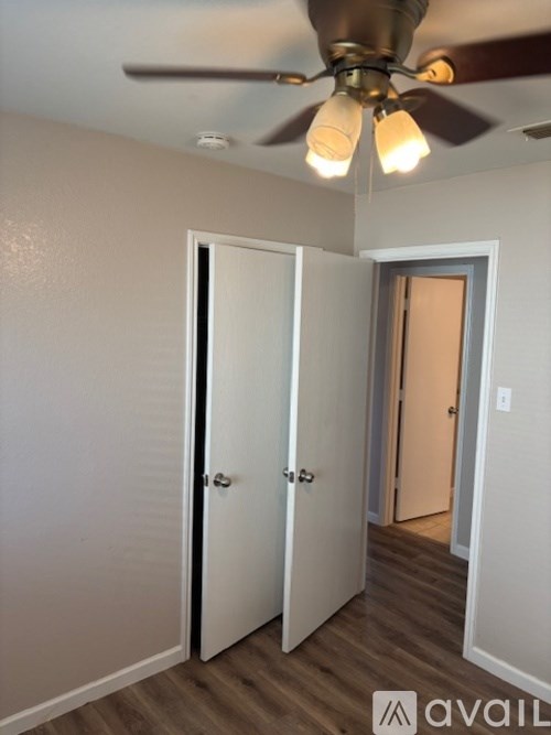 A room with a ceiling fan and three doors.