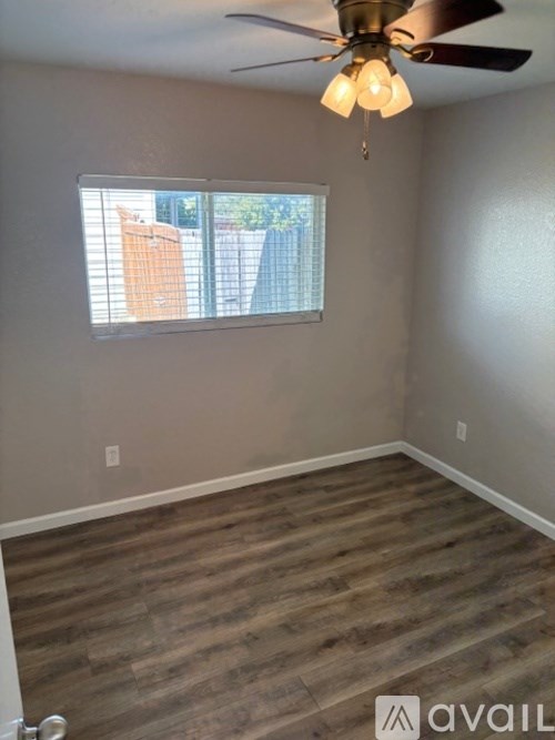 A room with a ceiling fan and a window with blinds.