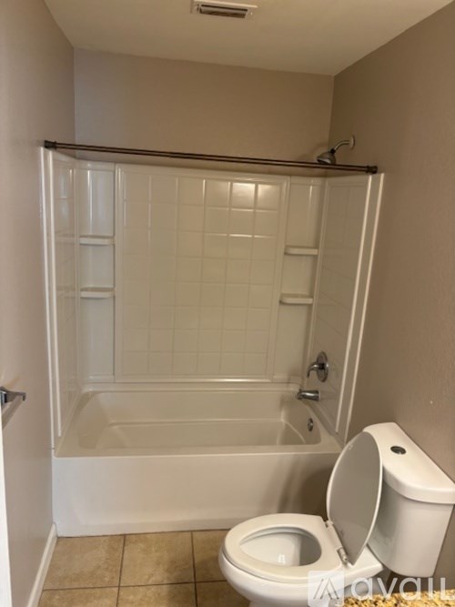 A white toilet is in a bathroom with a walk-in shower.