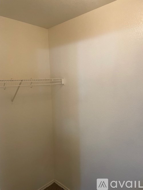 A white closet with a shelf and a hanger.