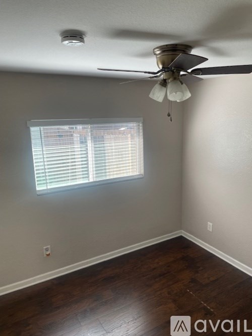 A room with a ceiling fan and a window with blinds.