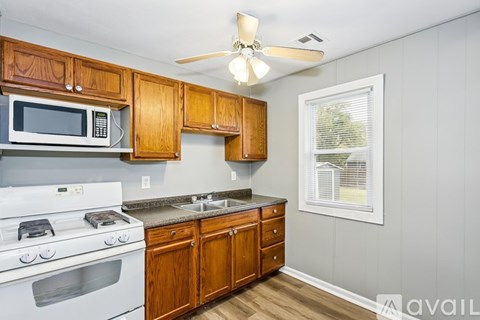 A kitchen with wooden cabinets and a white stove top oven.