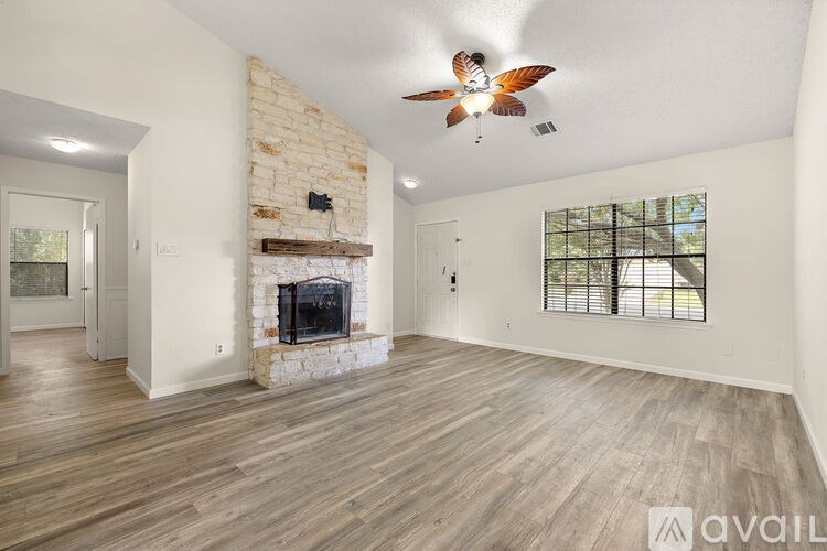 A spacious living room with a fireplace and a ceiling fan.