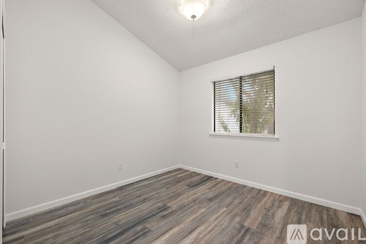 A room with wooden flooring and a window with blinds.