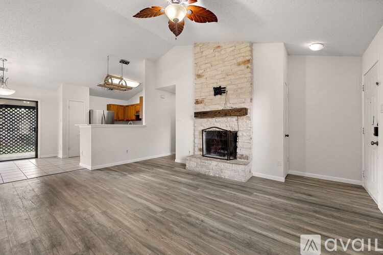 A living room with a fireplace and a ceiling fan.