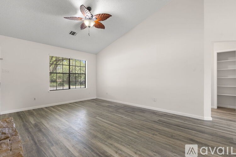 A spacious room with a ceiling fan and wooden flooring.
