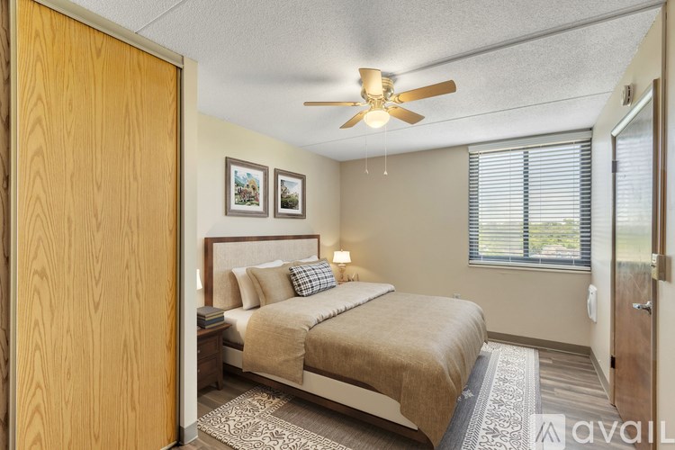 A bedroom with a bed, a ceiling fan, and two pictures on the wall.