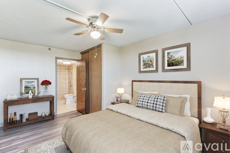 A bedroom with a large bed, a ceiling fan, and two pictures on the wall.