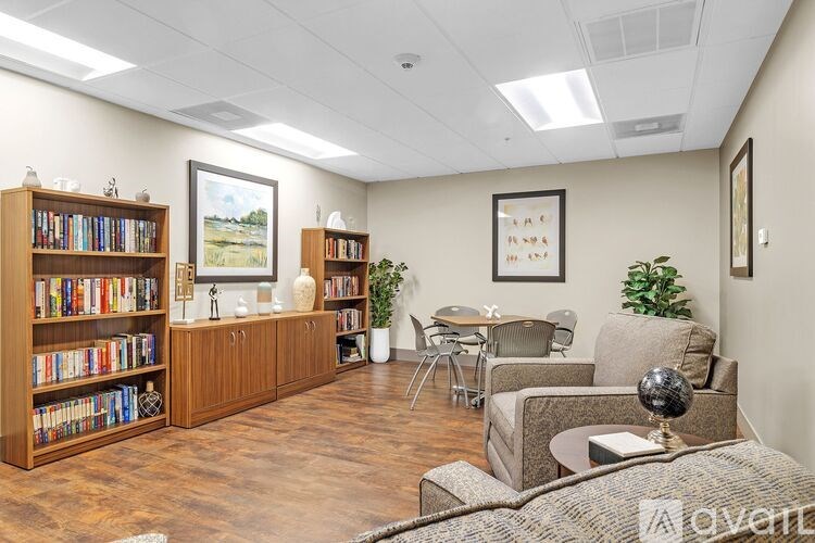 A room with a bookshelf, a sofa, a table, and a painting on the wall.