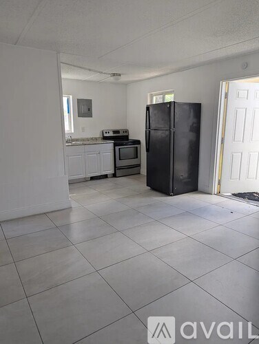 A kitchen with white cabinets and appliances, a refrigerator, and a microwave.